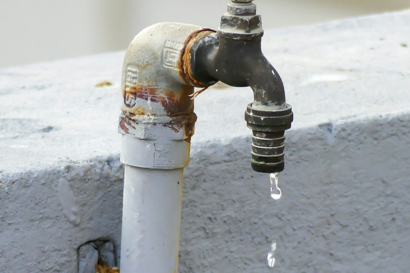 Tubo dell'acqua arrugginito con il rubinetto che gocciola